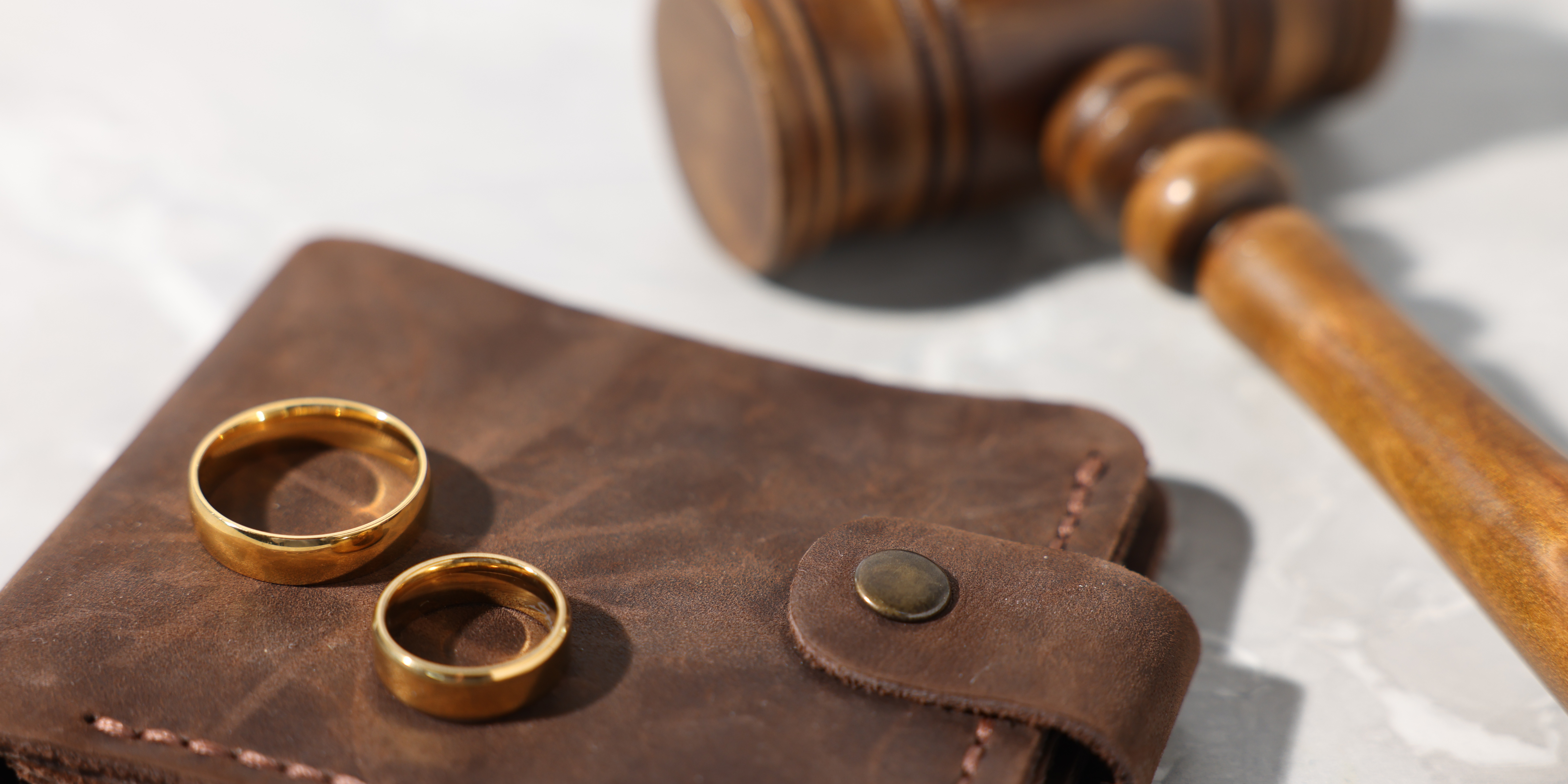 Wedding rings and a gavel on a desk representing divorce proceedings and alimony or spousal support
