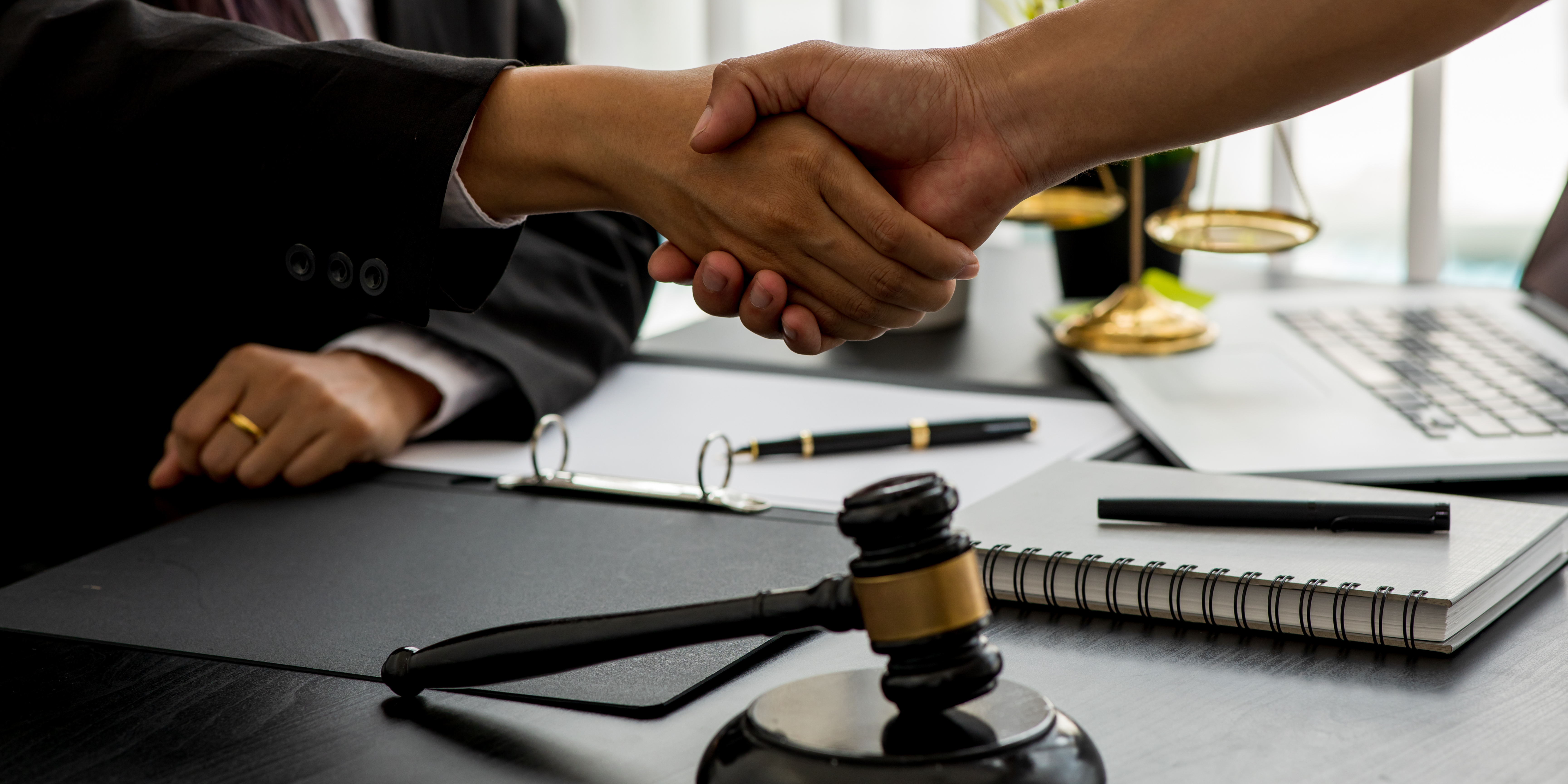 Attorney and client shaking hands over a desk with legal documents, representing hiring the right lawyer for a family law case