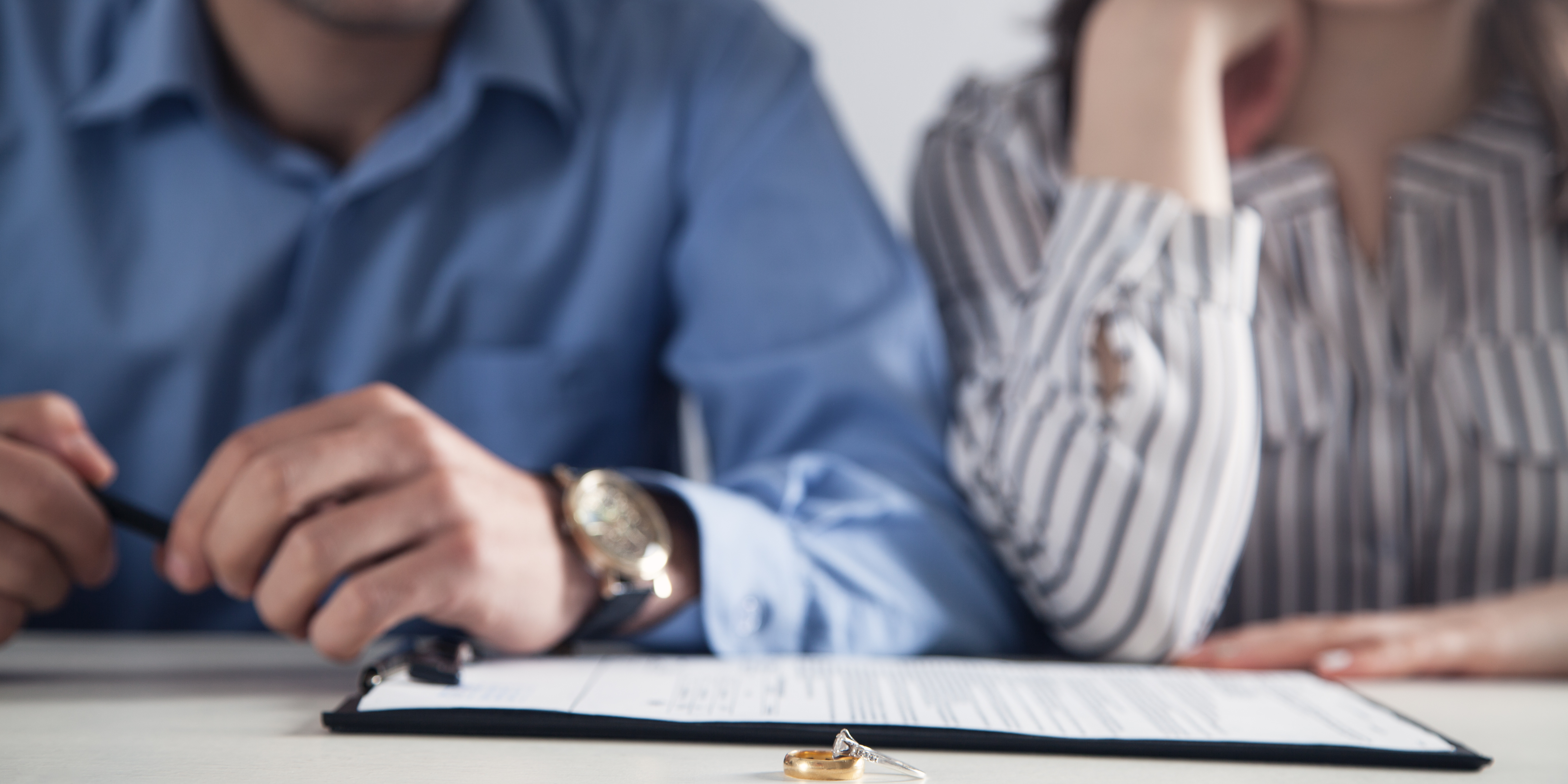 Close-up of a couple sitting at a table with divorce papers and wedding rings, symbolizing separation and decision-making during the COVID-19 pandemic.