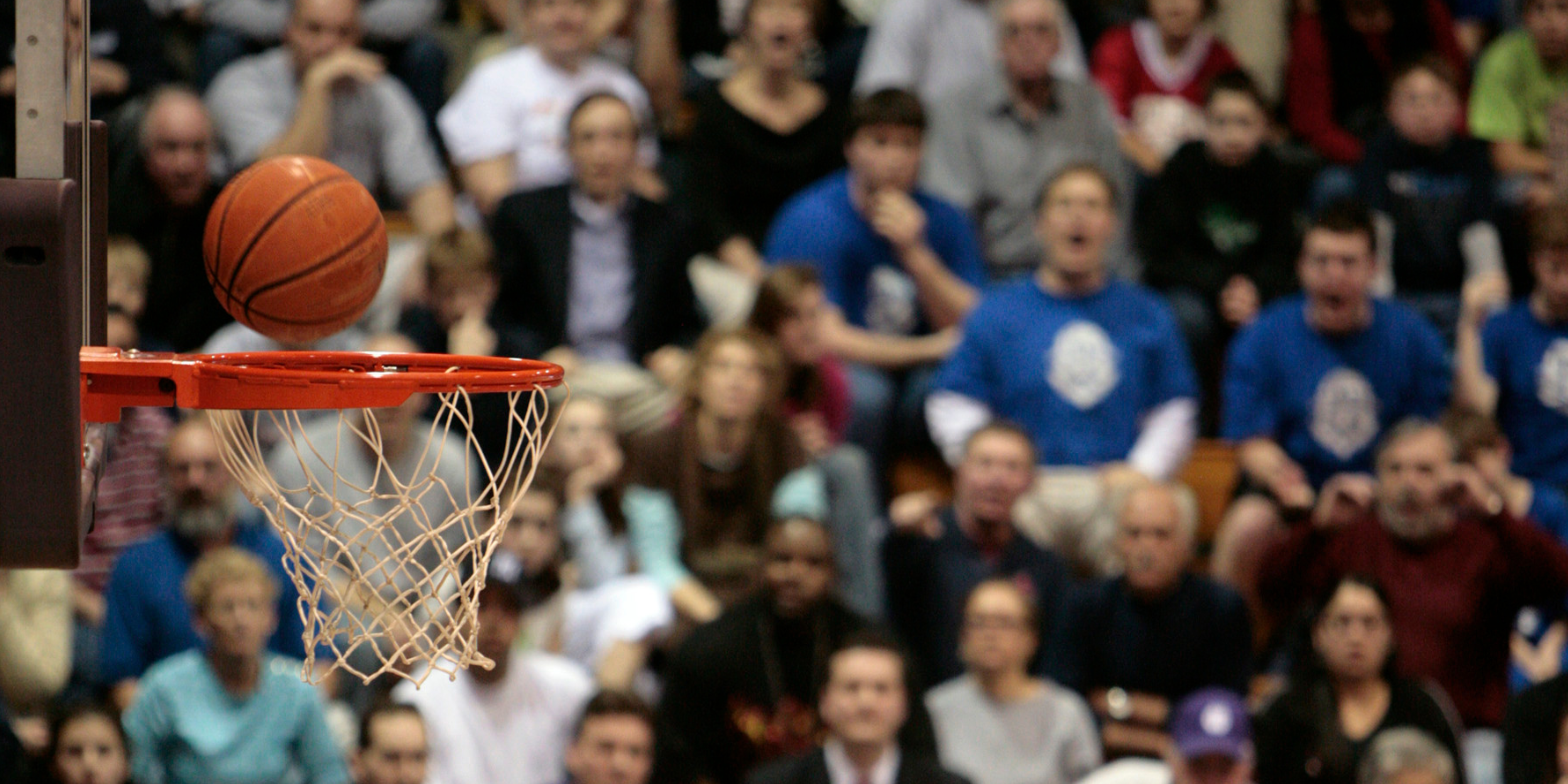 Basketball about to go through a hoop with a cheering crowd in the background, symbolizing preparation, focus, and smart planning during divorce season.