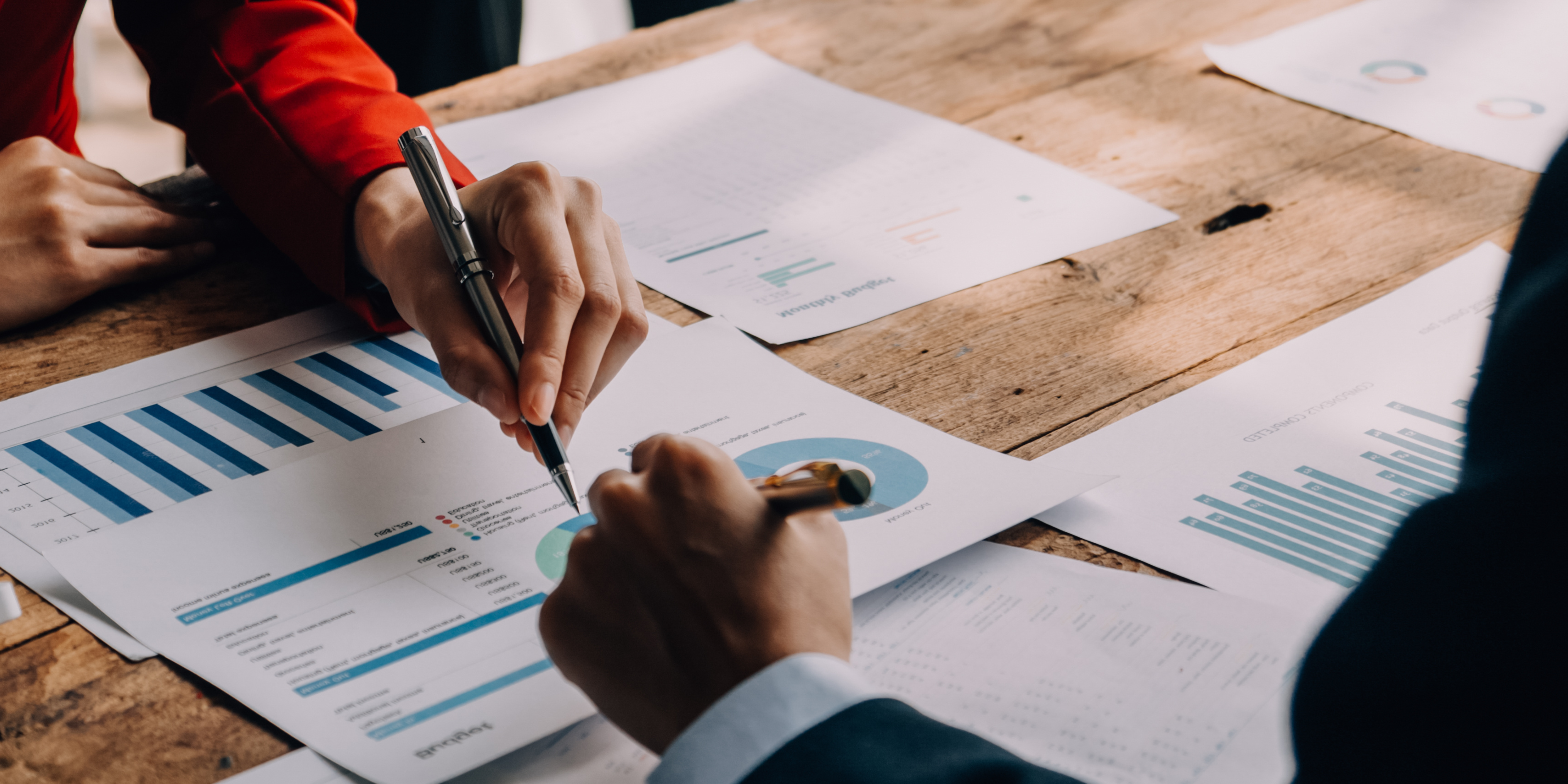 Close-up of two professionals reviewing financial charts and documents, symbolizing financial planning and organization after divorce.