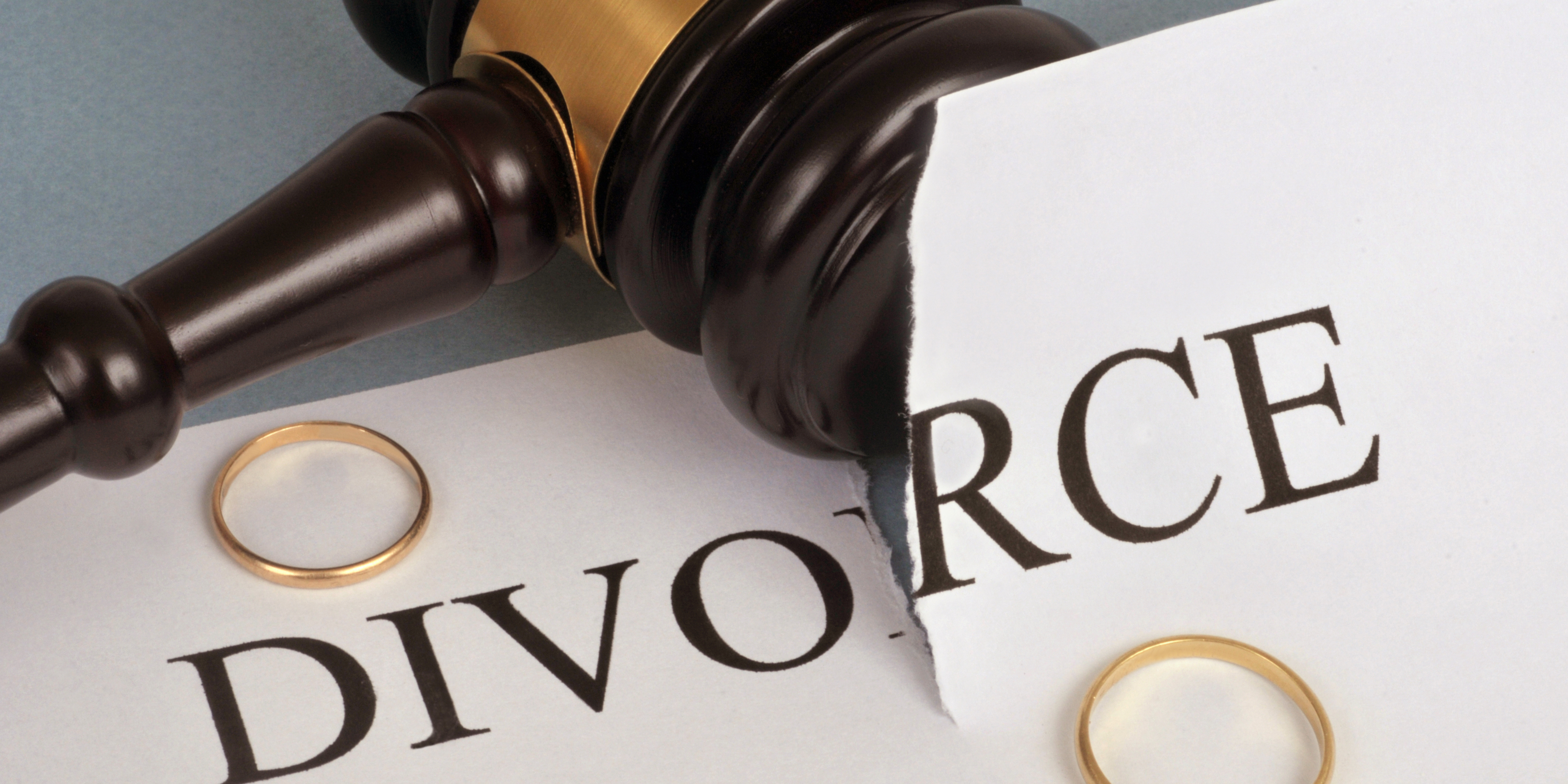 Close-up of a gavel and torn divorce document with two wedding rings beside it, symbolizing separation, decision-making, and new beginnings after marriage.