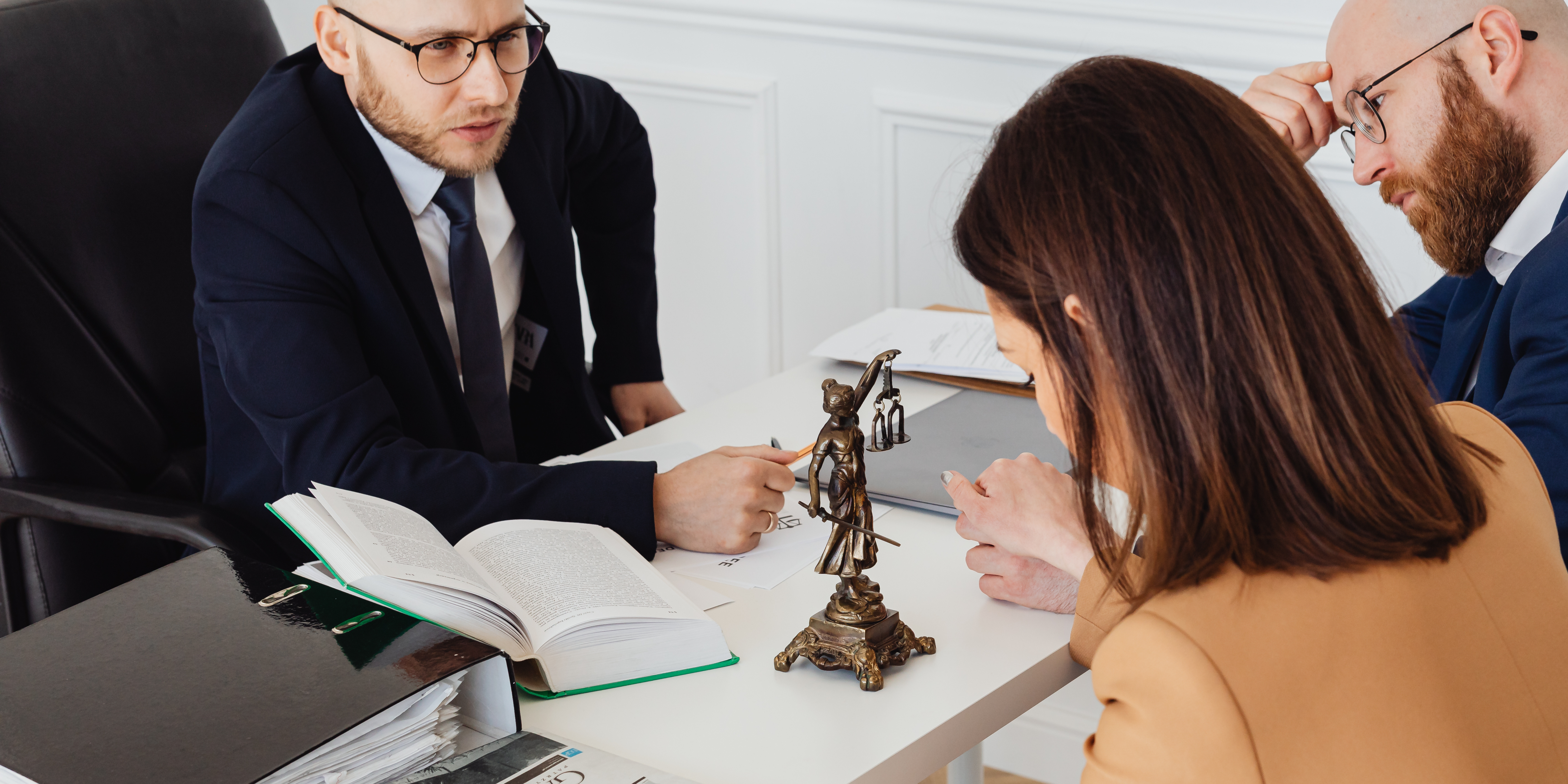 Couple meeting with a family law attorney, discussing legal strategy at a desk with law books and a Lady Justice statue.