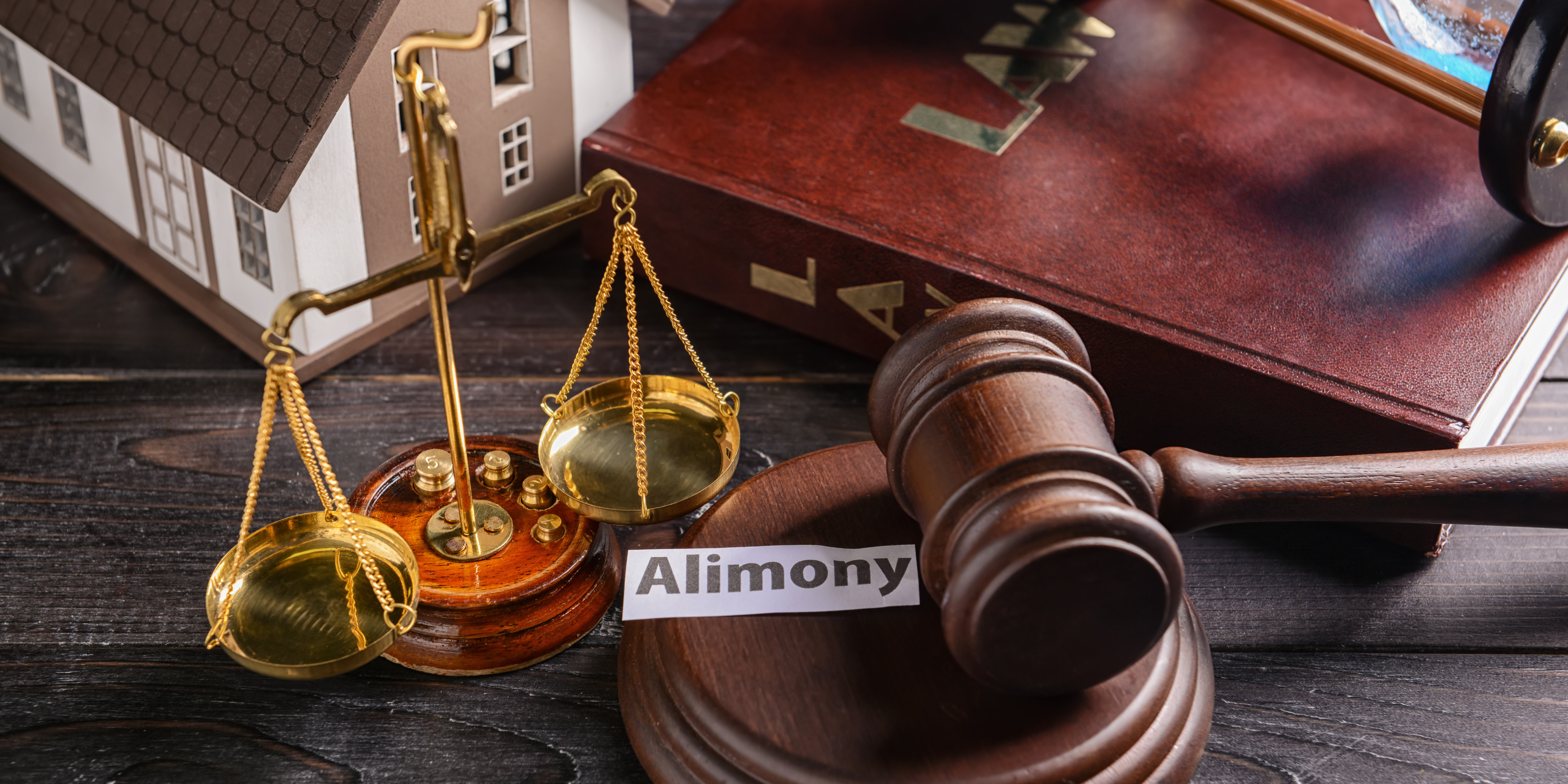 A judge’s gavel, a golden balance scale, and a law book next to a paper labeled “Alimony,” symbolizing spousal support decisions.