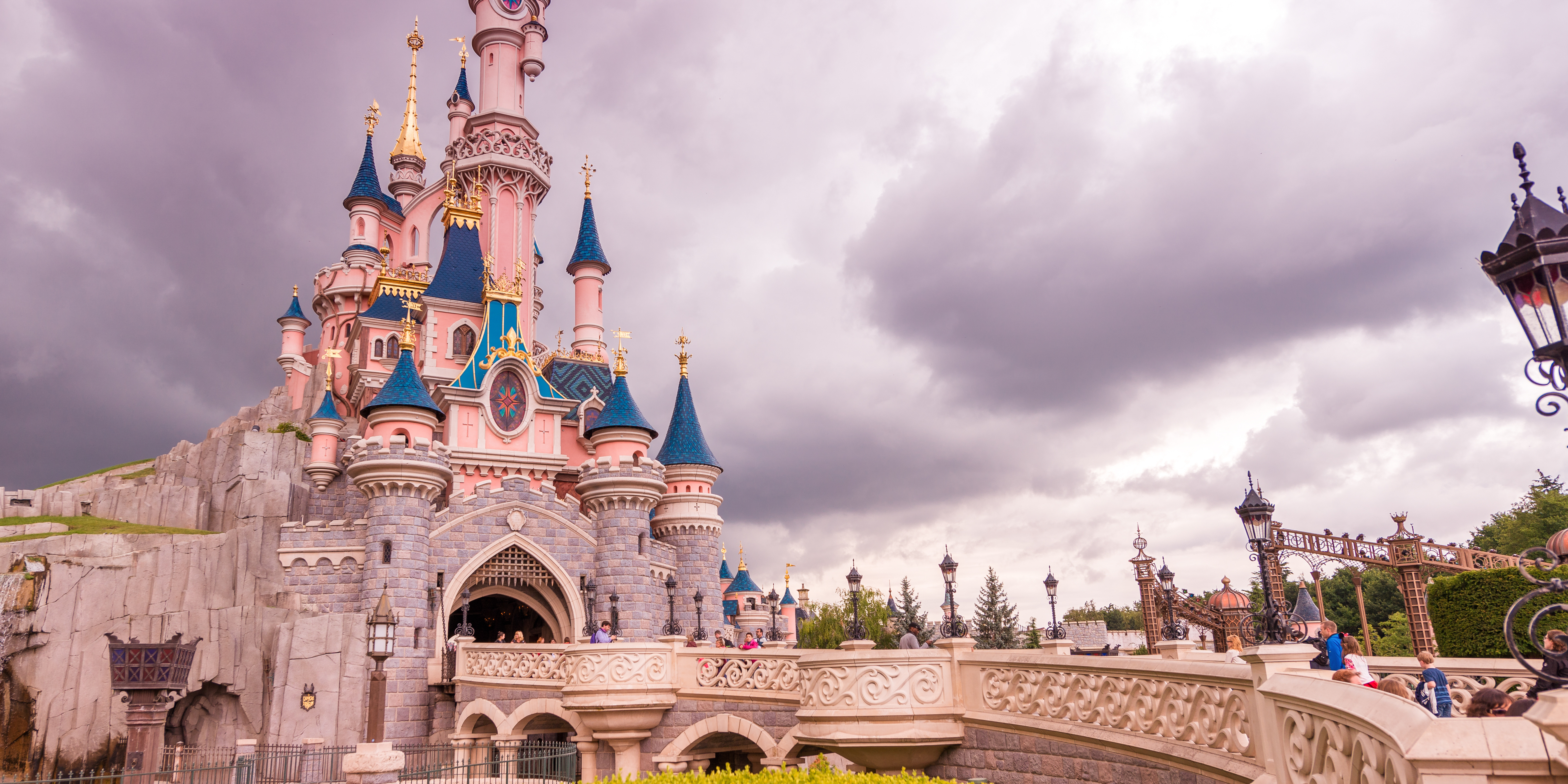 A bright, whimsical castle with families walking nearby, symbolizing a “Disneyland” parent who focuses on entertainment over structure.