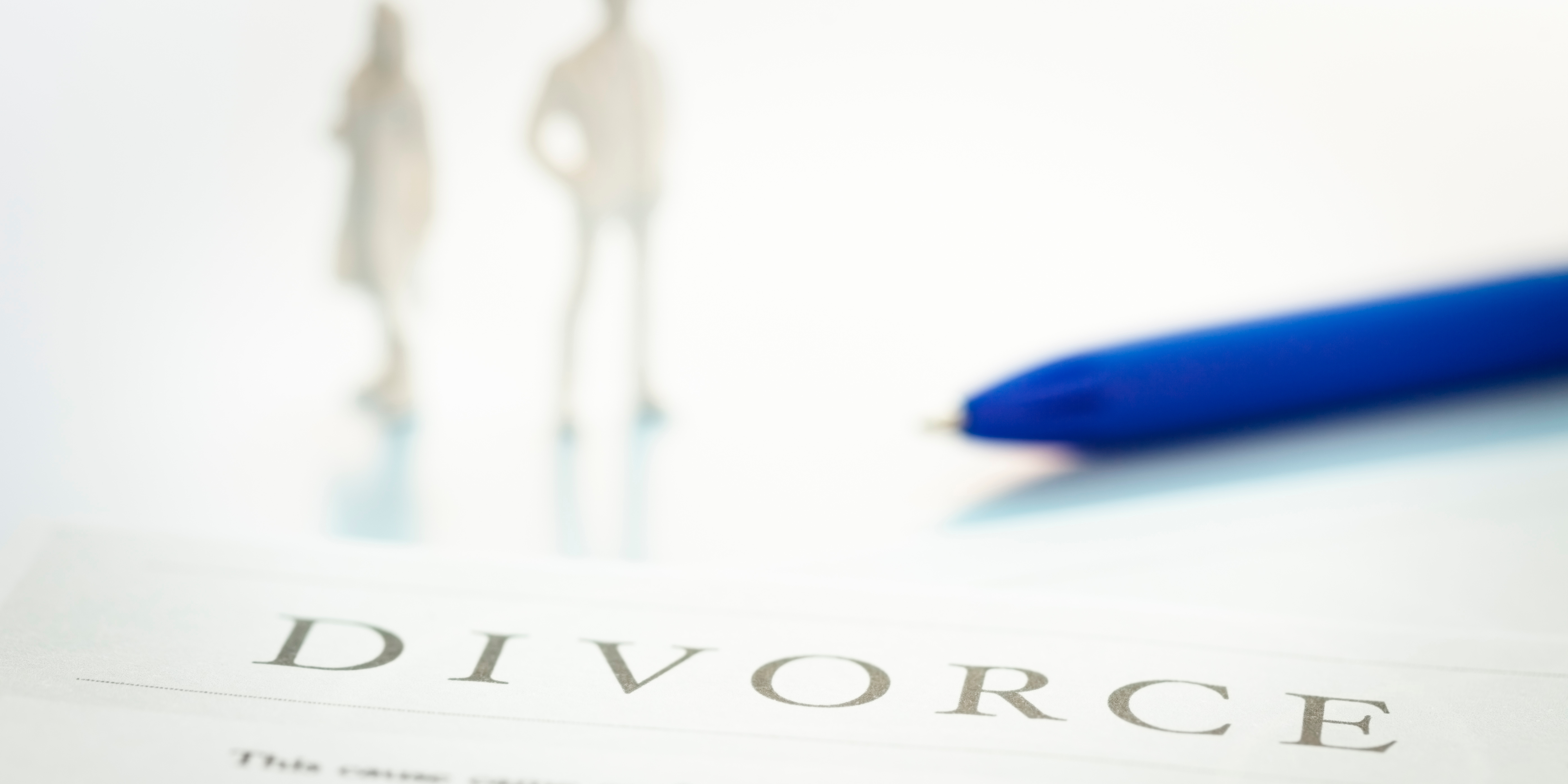 Divorce paperwork with blurred figures of parents in the background, symbolizing co-parenting, school-year transitions, and communication after separation.
