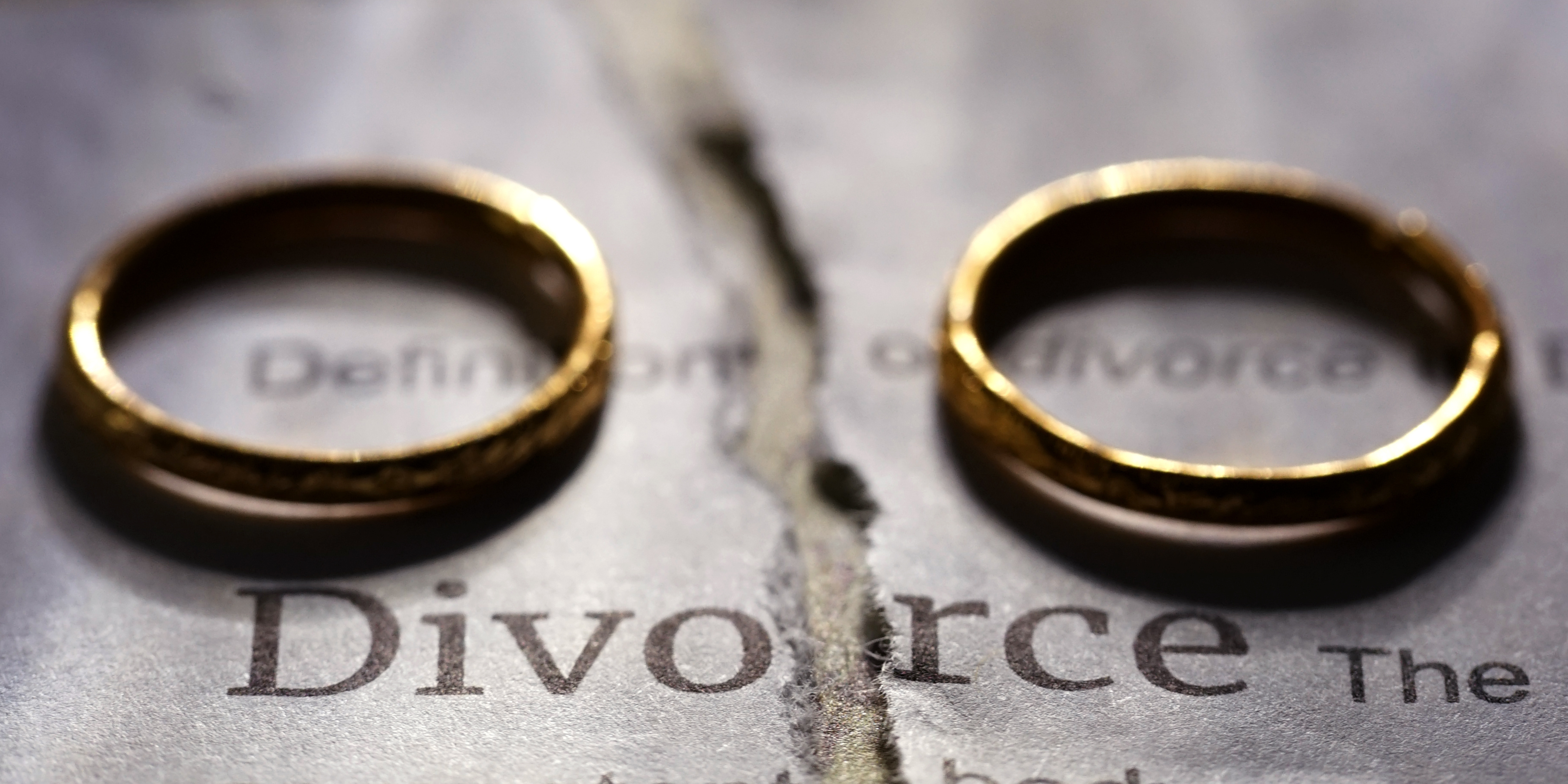 Two gold wedding rings placed apart on a torn paper labeled “Divorce,” symbolizing separation, choice, and the different paths to dissolving a marriage.