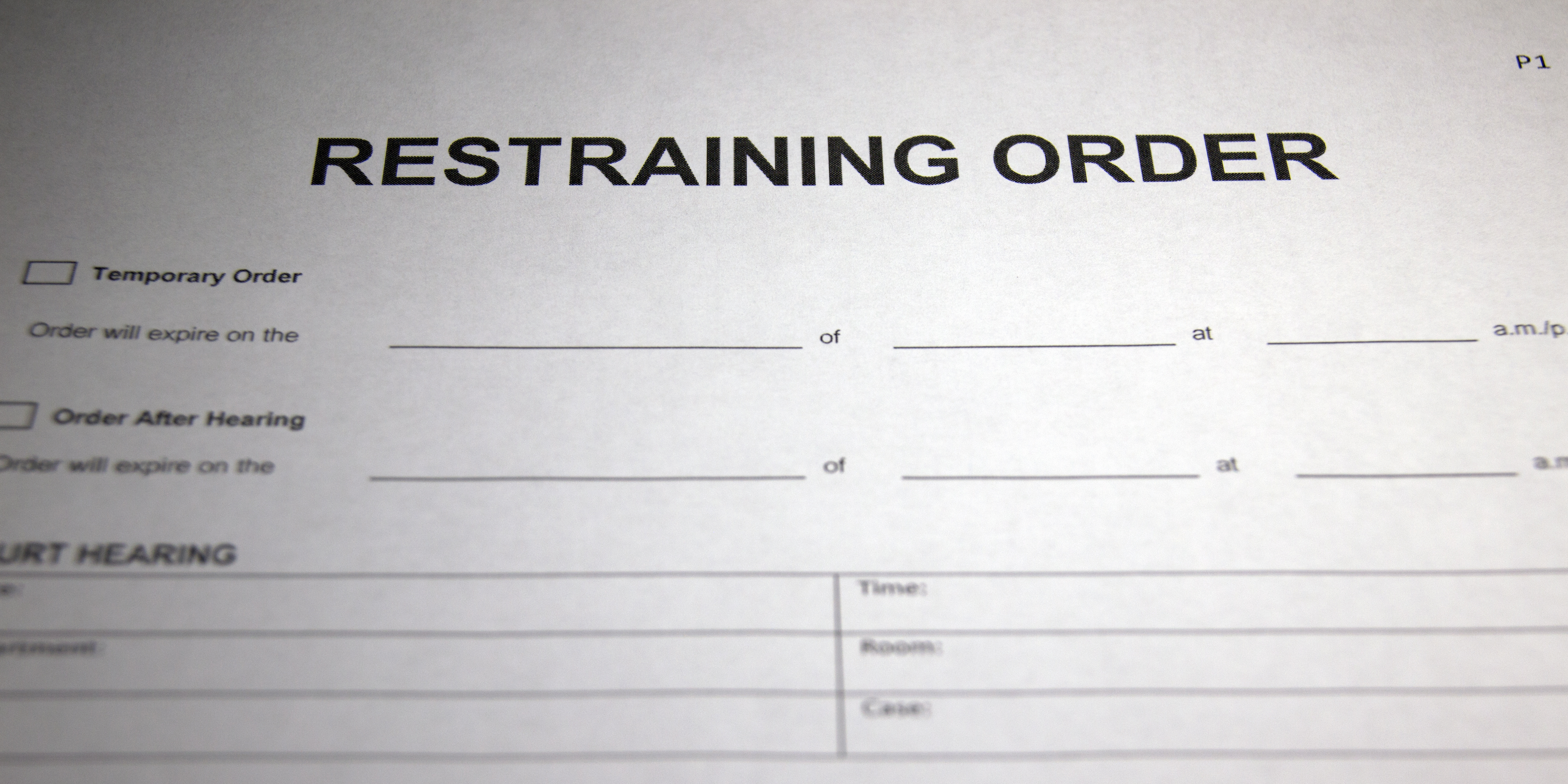 A close-up of a restraining order form with blank spaces and checkboxes for temporary and hearing orders.