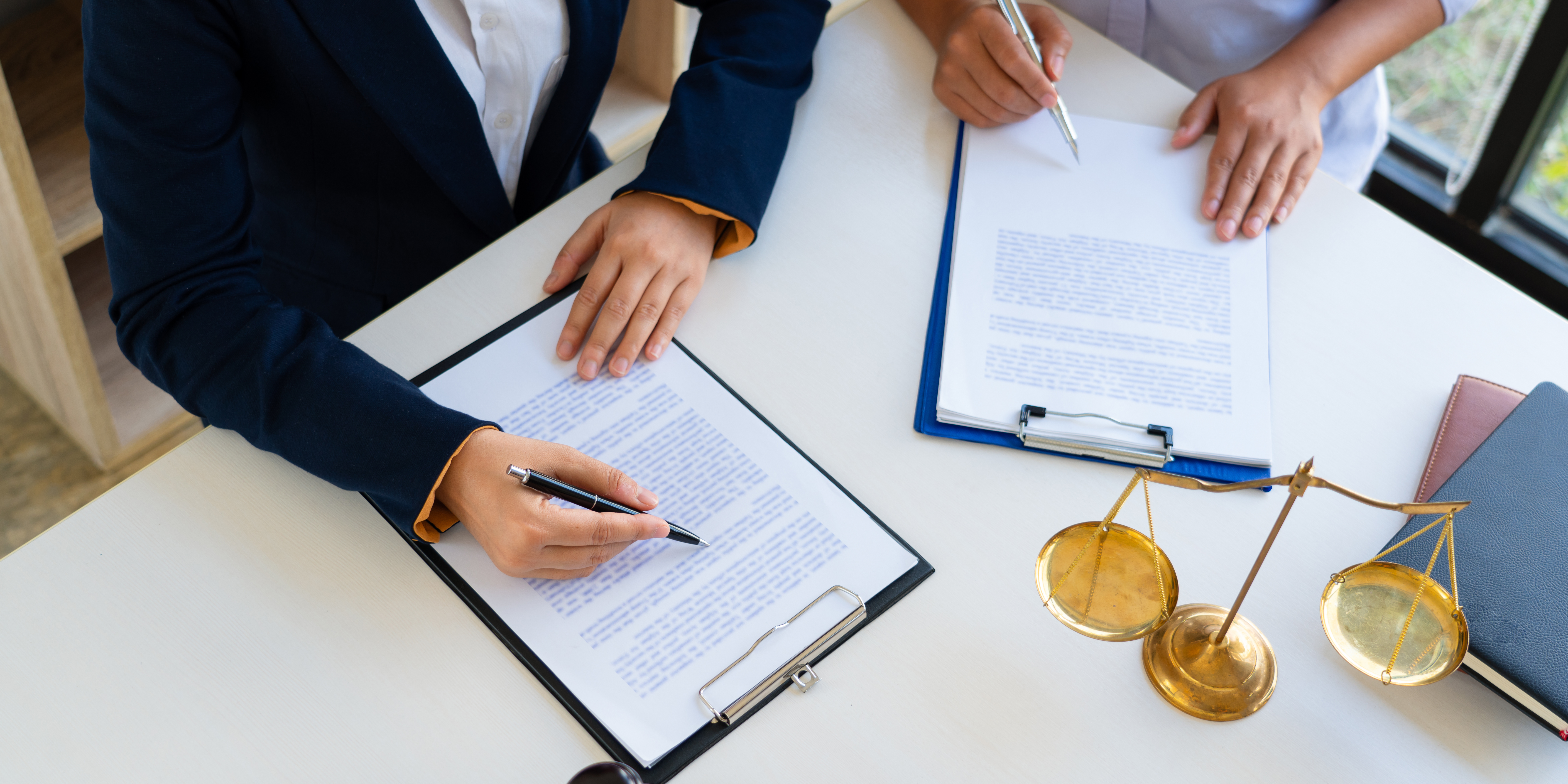 Two professionals reviewing legal documents with a golden justice scale on the table, symbolizing experience, fairness, and trusted legal guidance in family law matters.
