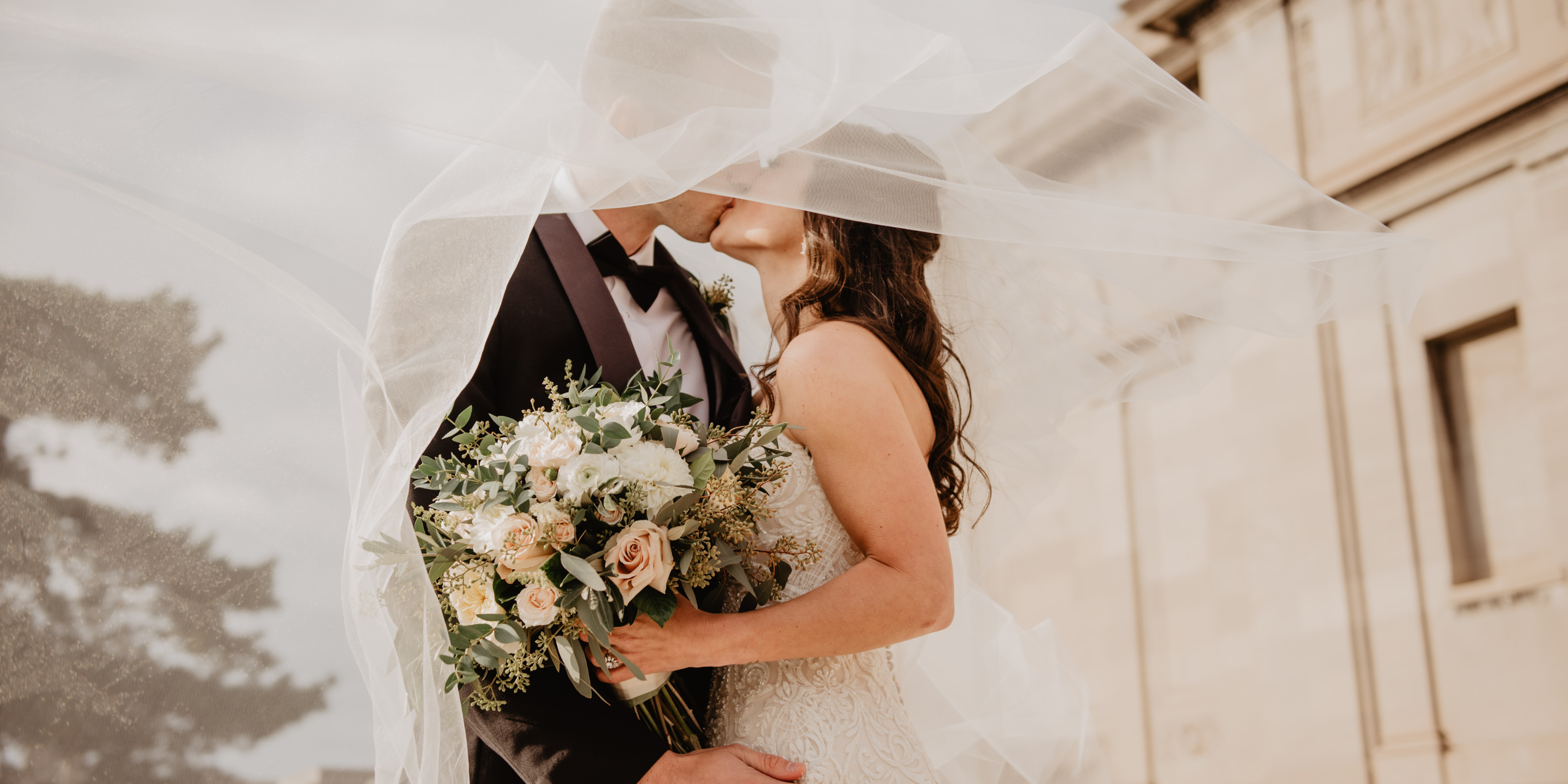 A bride and groom kissing under a sheer wedding veil, symbolizing the future of marriage.